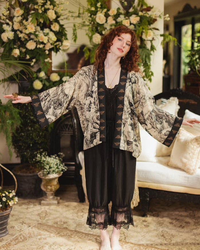 Woman in a floral kimono standing in an elegant room with floral decorations