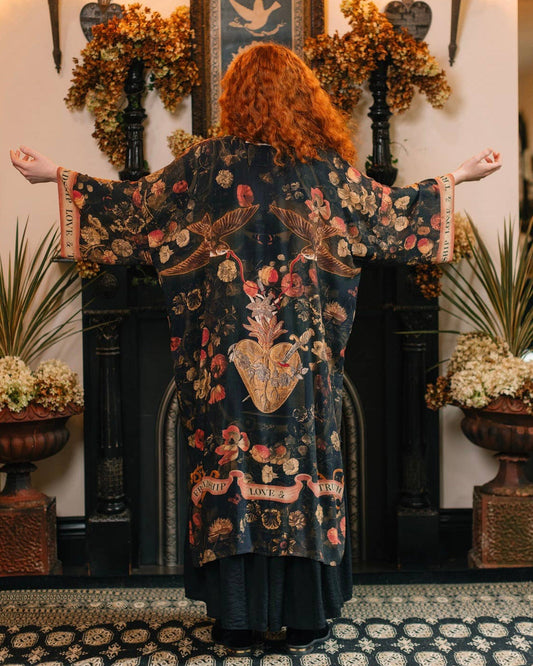 Person wearing a floral kimono in a decorated room with plants and wall art.